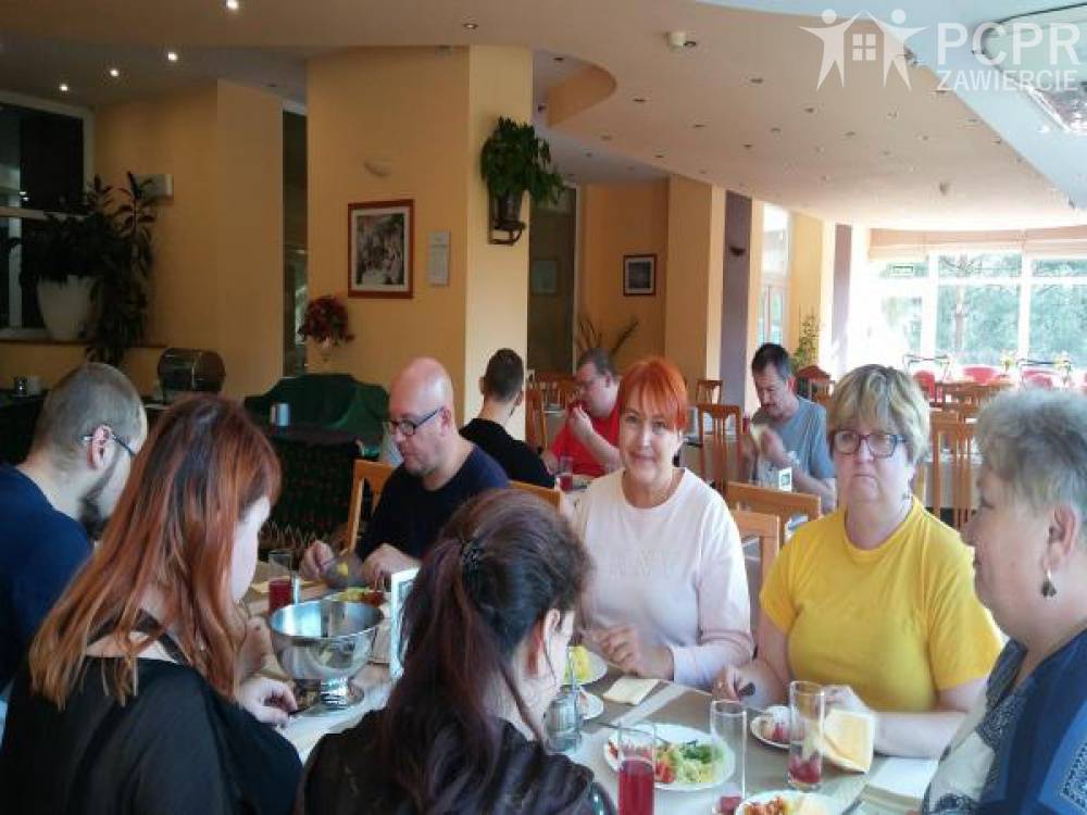 Zdjęcie: Grupa kobiet i mężczyzn siedzi przy stole w trakcie obiadu